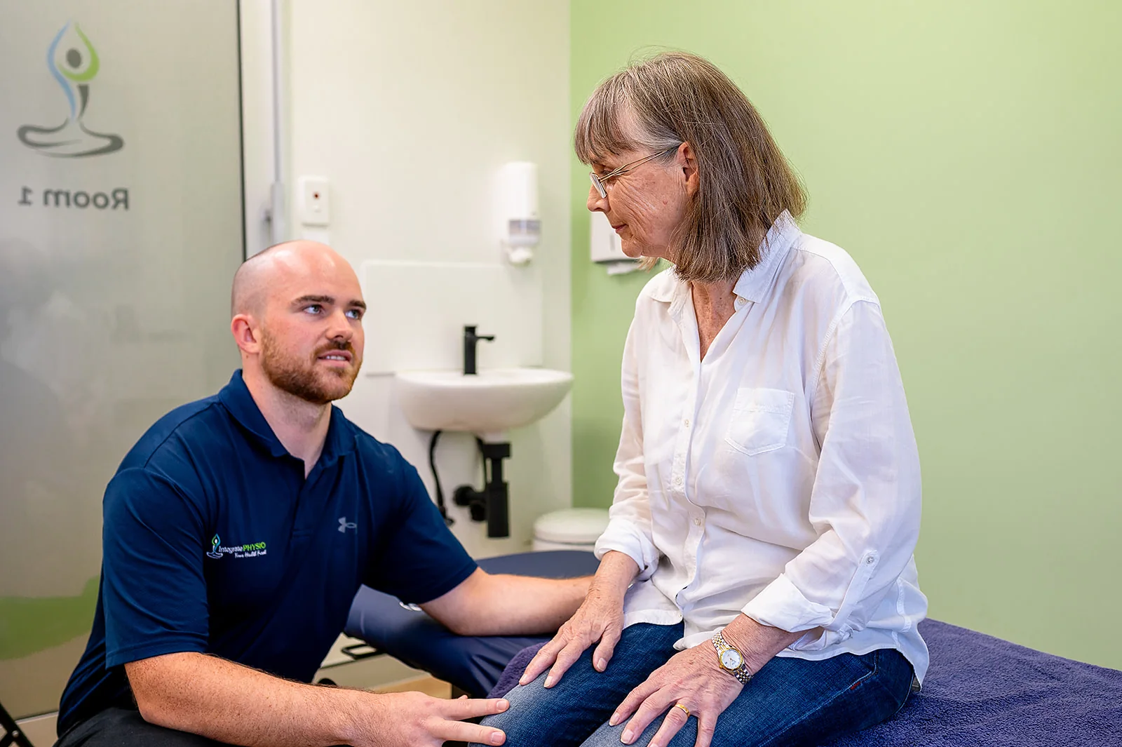 A clinician assessing a seated patient’s knee