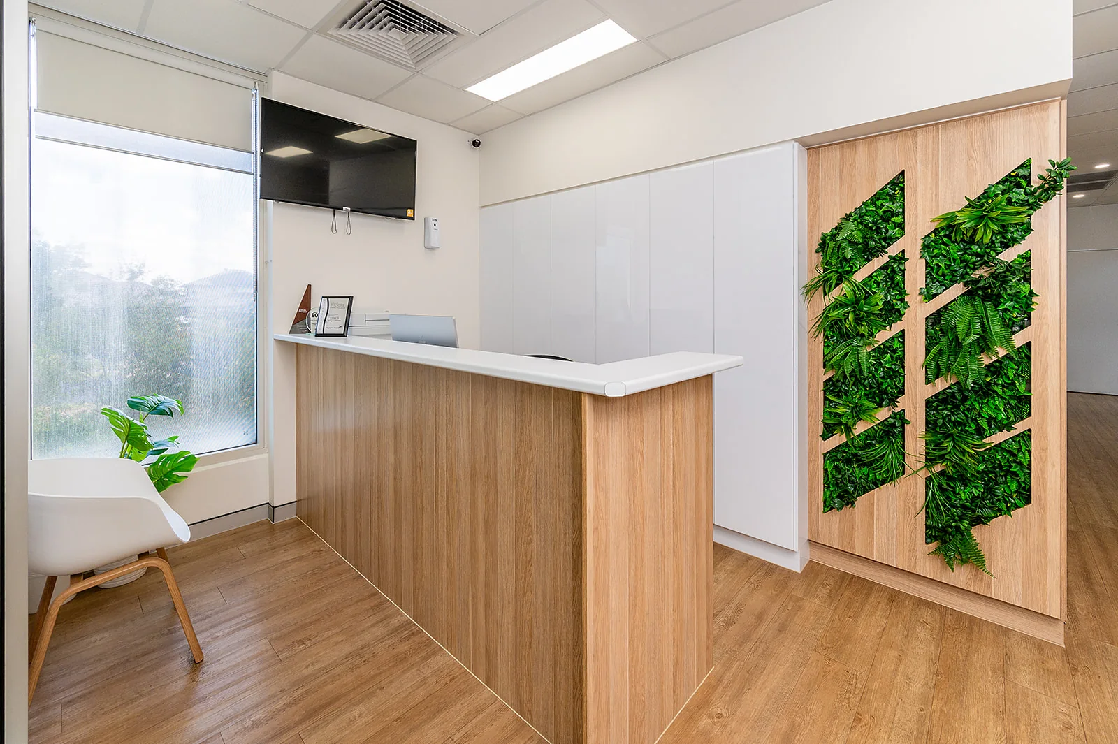 The reception area with timber desk and greenery